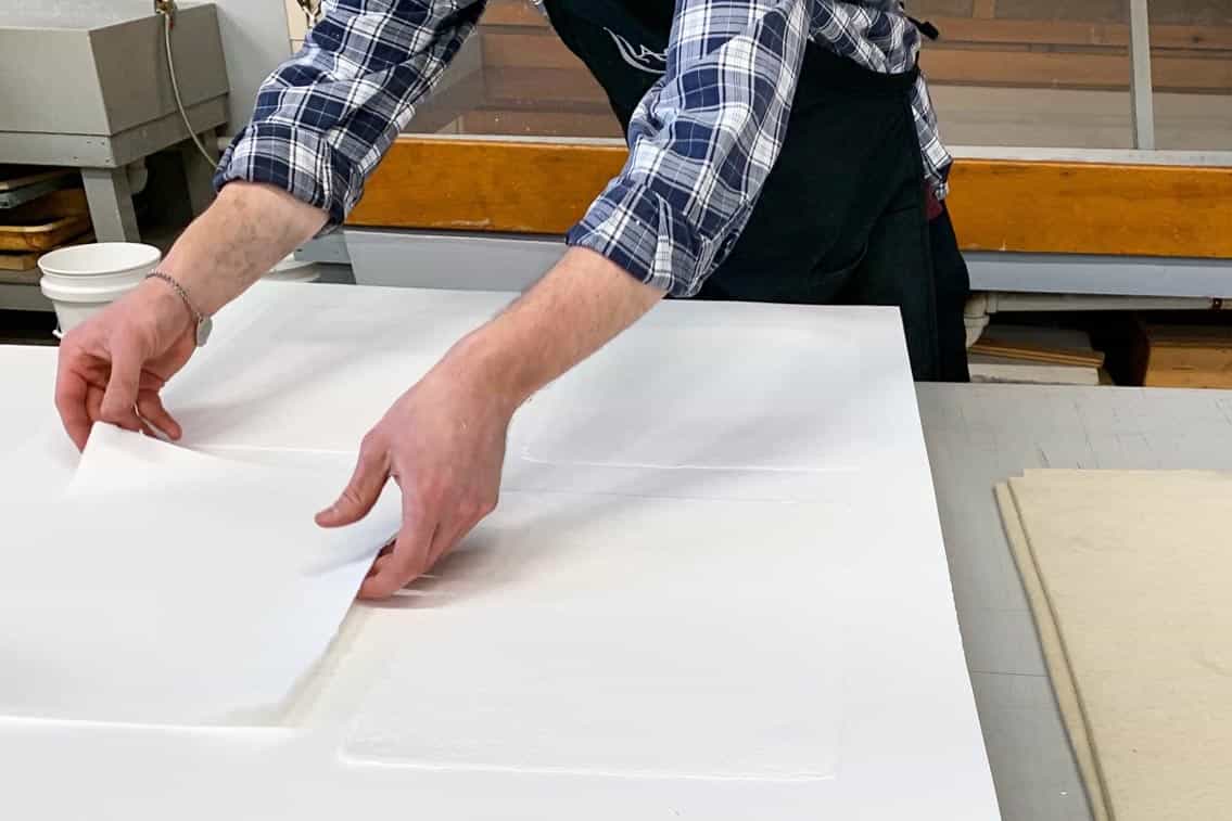Printer Michael Rahn placing handmade paper sheets on blotters for the drying box.